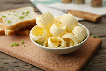 Bowl with fresh butter and bread on wooden background