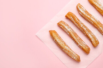 Parchment with tasty churros on color background
