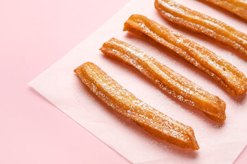 Parchment with tasty churros on color background, closeup