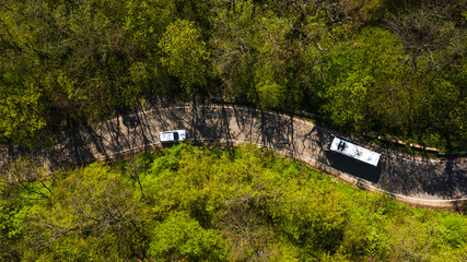 a winding country road with a bus and car moving along it. Top view of the Sochi serpentine road.