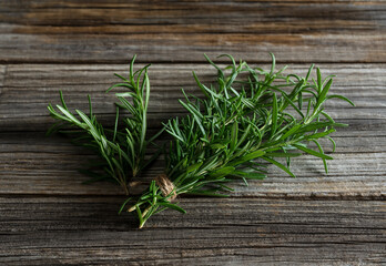 A bunch of rosemary placed against a wooden background.