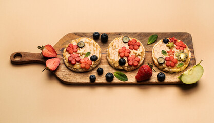 Summer dessert multigrain sandwiches with peanut butter with fruits and berries with maple syrup on a wooden board, top view. Healthy food concept