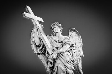 Medieval outdoor statue of an Angel with the Cross by Ercole Ferrata on Sant'Angelo Bridge in black and white with vignetting effect in Rome, Lazio region, Italy