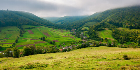 village in the valley of carpathian mountains. rural landscape in early autumn. fields and pastures on the hillside meadows. wonderful nature scenery in the morning
