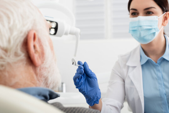 senior man having teeth examination by dentist in latex gloves with mirror in clinic.