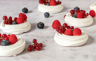 Meringues or mini Pavlova. Sweet dessert decorated with different berries. Fresh baking concept. Selective focus.