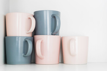Coffee mugs stacked background. Ceramic mugs on white shelf. Coffee time background. Simple tea...