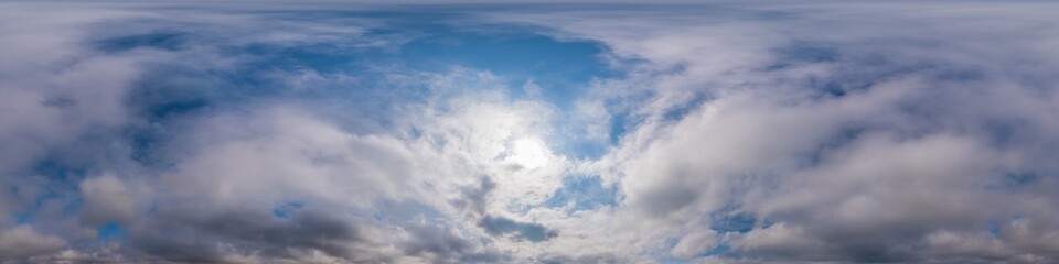 Obraz premium Blue evening sky seamless panorama spherical equirectangular 360 degree view with Cumulus clouds, setting sun. Full zenith for use in 3D graphics, game and aerial drone panoramas as sky replacement.