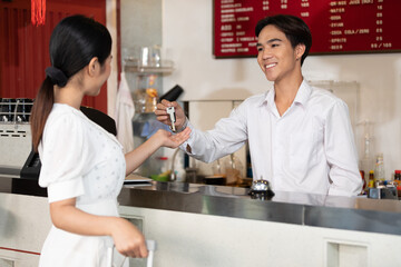 male receptionist or hotel front desk smiling and giving keycard to a customer
