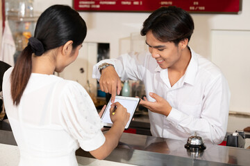 woman guest write signature for check in hotel from receptionist on tablet