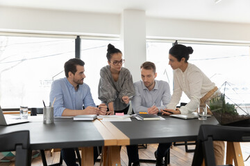 Fototapeta premium Diverse colleagues employees team analyzing, working with financial project statistics, gathering in boardroom, coworkers involved in briefing, business partners brainstorming ideas at meeting