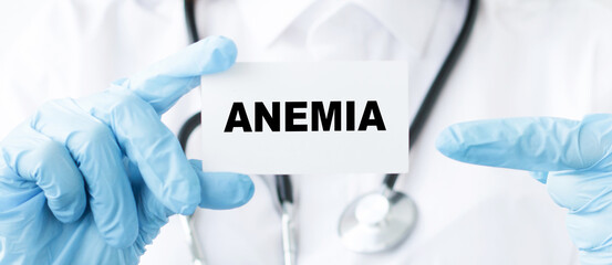 Doctor holding a card with text ANEMIA, points his hand at the inscription, medical concept