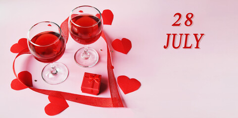 calendar date on light background with two glasses of red wine, red gift box and red hearts with copy space. July 28 is the twenty-eighth day of the month