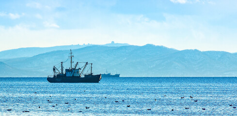 fishing boat in gray morning on Pacific ocean off the coast of the Kamchatka Peninsula