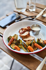 grilled chicken with vegetables with sauce on a wooden table on the terrace of a local diner
