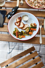 grilled chicken with vegetables with sauce on a wooden table on the terrace of a local diner
