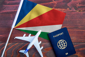 Flag of Seychelles with passport and toy airplane on wooden background. Flight travel concept.
