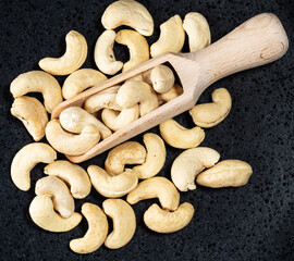 top view of wooden scoop in cashew seeds on black