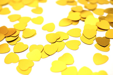 Gold color confetti on a white isolated background. Love and romance abstract background. Saint Valentine theme. Selective focus