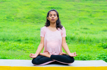 Young Indian woman practising yoga, doing Ardha Padmasana exercise, meditating in Half Lotus pose,...