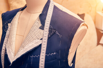 Semi-ready jacket on mannequin with measuring tape across neck. Suit tailoring in process of...