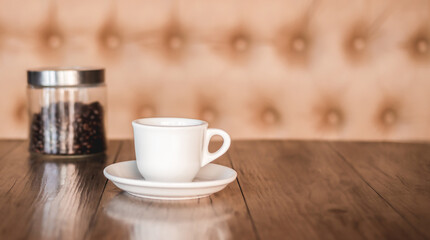Hot coffee americano on the old wooden table. A cup of coffee on a plate. Americano black coffee. Coffee cup on the wooden background. Hot Coffee.	