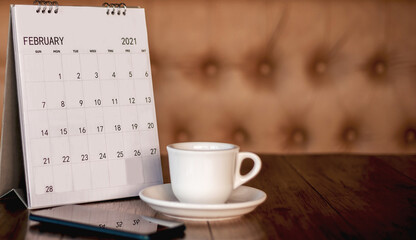 Calendar, mobile, coffee cup Placed on an old wooden table is a planning idea for success.