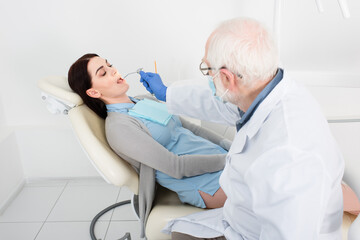 Fototapeta na wymiar senior dentist making teeth treatment of patient in dental chair.