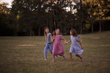 Naklejka na ściany i meble Three little girls together in nature. Walking and talking.