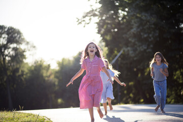 Three little girls running in the park. Focus is on foreground.