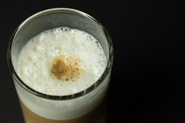 Glass of latte coffee on black background