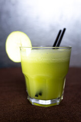 green smoothie in a glass glass with an apple and a tube