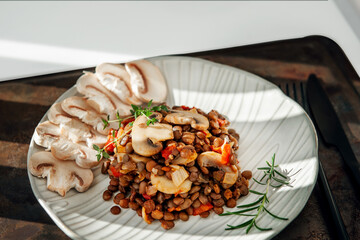 lentils with sliced mushrooms and vegetables. Vegan food - stewed carrots, peppers, onions and lentils with fried mushrooms. Close-up