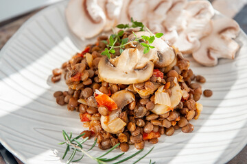 lentils with sliced mushrooms and vegetables. Vegan food - stewed carrots, peppers, onions and lentils with fried mushrooms. Close-up