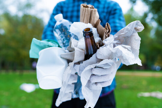 Ecology volunteer teamwork. Male activist in work gloves collect plastic paper glass trash in park. Group of people are sorting garbage and putting it in bag. Concept of environmental pollution. - Powered by Adobe