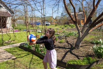 Teenage girl playing with a volleyball ball in a blooming garden in early spring