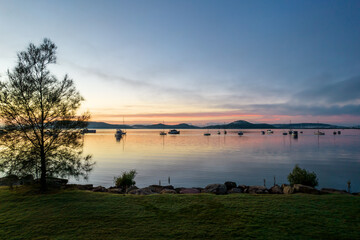 Sunrise waterscape with boats, light cloud and fog