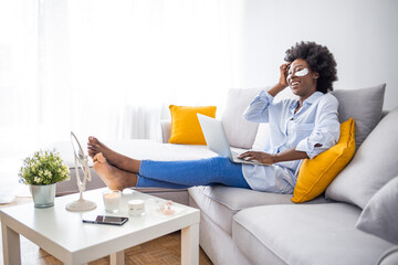 Woman having beauty mask and working from home on laptop. Young woman with wrinkles and a silver patch under eyes. Collagen mask and spa concept. Copy space. Summer skin care.