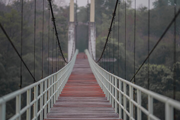 Obraz premium The suspension bridge has a wooden floor with a light green steel handle. Located in Thailand