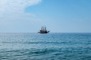 Single pirate schooner among blue water off the coast of Alanya (Turkey). One tourist ship on the horizon. Background with copy space