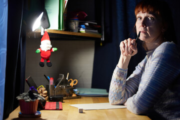 Portrait of caucasian adult woman is writing at the table at home. High resolution photos