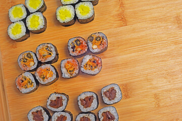 Sushi set lies on a wooden board, maki. Lots of sushi, rice, nori and filling, fish, seafood, place for food text