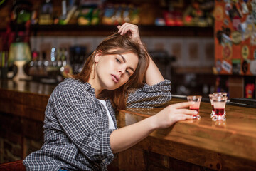 Drunk woman holding a glass of whisky or rum. Woman in depression. Young beautiful woman drinking alcohol. Scotch whiskey glass isolated at bar or pub in alcohol abuse and alcoholic concept