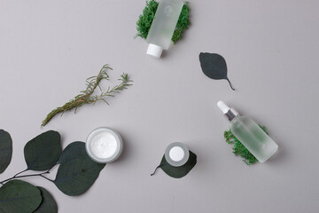 Obraz na płótnie Canvas Cosmetic skin care products with eucalyptus and moss on grey background. Flat lay.