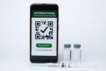 A picture of smartphone with fake International Certificate of Vaccination on it, two doses of vaccine and injection syringe insight. 2 doses of vaccine needed for the immunization.
