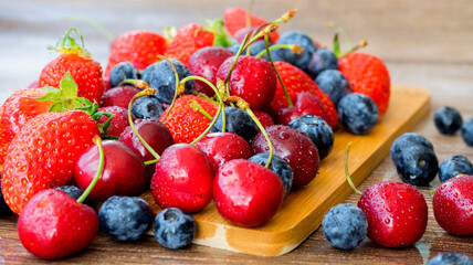 Assorted berries close-up: strawberries, blueberries, cherries. Image with selective focus