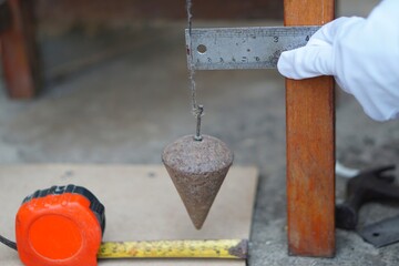 Carpenter is measuring by using measure tape and plumb bob at construction site in Thailand. Concept tools for carpenter to measure and repair things. 