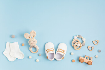 Baby shoes, bib and teether on pastel background. Organic newborn accessories - obrazy, fototapety, plakaty