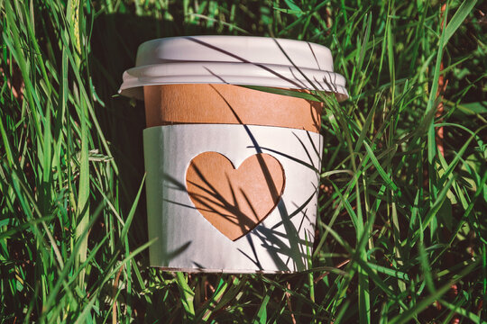 paper cup of natural coffee in green grass