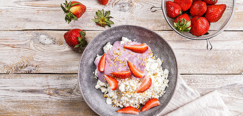 Food banner. Farmers delicious cottage cheese with slices of ripe strawberries. Breakfast ideas: dairy products and juicy fruits Organic food on your table Rustic table background Top view Copy space